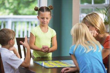 Little girl plays board game with family.