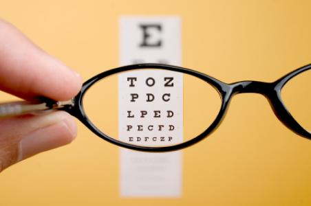 Looking through eyeglasses at an eye exam chart.