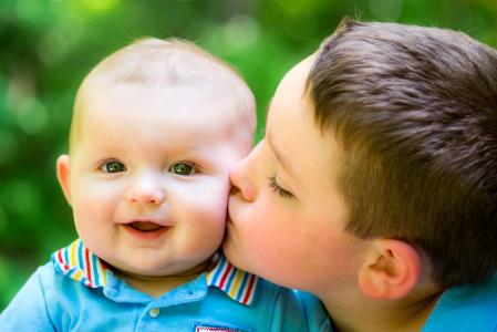 Happy baby boy kissed by his older brother.