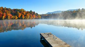 Herbstanfang am See mit buntem Laub spiegelnder Wasseroberfläche