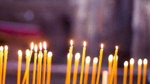 Close-up of many, thin, yellow beeswax candles in an Orthodox church.