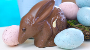 Australian milk chocolate Bilby Easter egg with eggs in nest against a blue and white background.