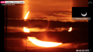 Screenshot from a timeanddate.com live eclipse broadcast showing a partially eclipsed Sun rising in Ontario, Canada. The yellow Sun looks like bright devils horns rising from the horizon. 