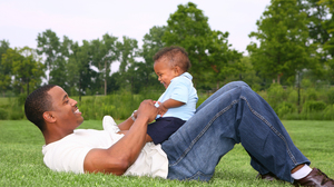 A father and his little son playing on grass.