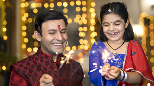 A father and daughter in Indian clothing playing with sparklers.