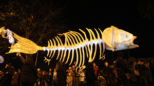 Image of a large fish skeleton tableau during the  Dragon of Shandon Samhain Parade on Halloween night in Cork City. People stand under the skeleton.