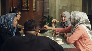 A group of Asian Muslims eating iftar food around a table.