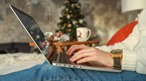 A pair of hands on a laptop with Christmas decorations in the background.