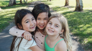 Happy and healthy mixed ethnic young little girls hugging and smiling in the park.