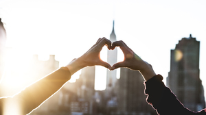 Heart shape with female hands in the Sun against the New York City skyline.