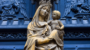 Old statue of Virgin Mary holding baby Jesus outside a Church.