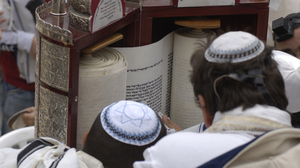 Jewish worshippers reading from Torah scroll