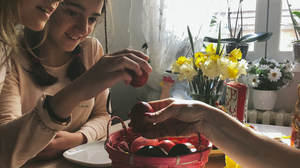 Family celebrating easter with cracking red-dyed eggs against each other.