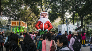 A crowd looking at a Santa Clause statue in a park.