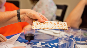 Matzo bread being passed over a traditional Seder table.
