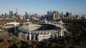 Aerial view of Melbourne Cricket Ground with the city's skyline in the background.