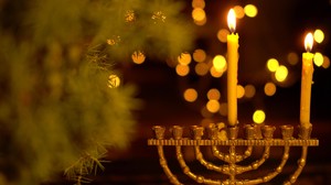 Golden menorah with one candle and the shamash lit.