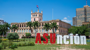 Historic building with the Paraguayan flag flying on top and "Asunción" spelled out in large red and white letters in front of it.