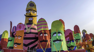 Big heads with prominent moustaches made of paper with bright colours in pink, green, yellow, and blue.