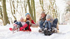 Smiling family sledging in the snow.