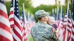 American soldier looking at flags with his daughter.