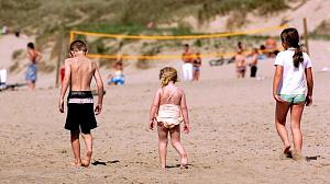 Barn i badetøy leker på sandstrand