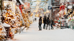 People in a snow filled old Quebec with Christmas lights.