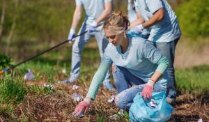 Woman picking up trash in a park.