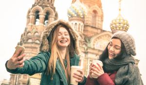 Two smiling girls with coffee cups taking a selfie in Saint Petersburg, Russia.