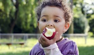 Child eating a red apple.