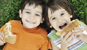 Young kids eating a sandwich.