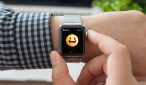 An Apple Watch with a smiley emoji on person's arm.