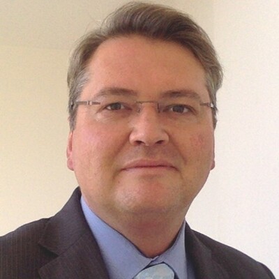 Headshot of a man in a suit smiling.