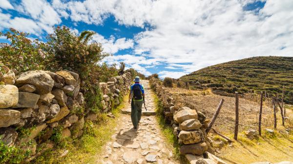 Female backpacker walking on ancient Peruvian trail.