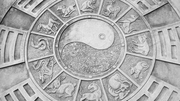 A yin and yang symbol surrounded by the Chinese zodiac pictures on a stone in the ground in Fengjing, China.