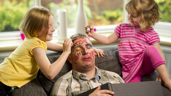 Two young girls putting makeup on their father.