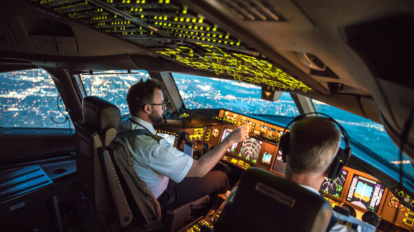 Flight deck (cockpit) of a Boeing commercial airliner at twilight with two pilots.