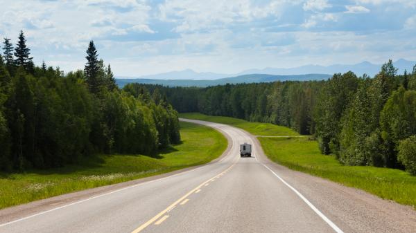 Recreational Vehicle on empty road of Alaska Highway Alcan in boreal forest taiga landscape south of Fort Nelson, British Columbia, Canada.