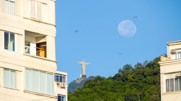 Christ the Redeemer and the Moon setting seen from Copacabana neighborhood in Rio de Janeiro.