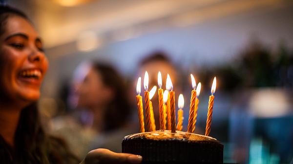 Girl with birthday cake and candles in front of blurry background