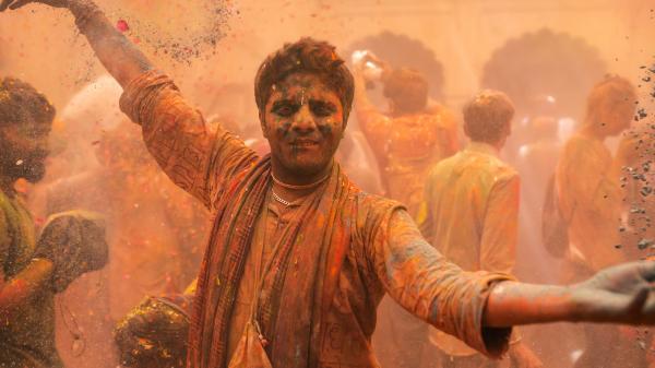 Photo of a dancing man, covered in colorful powder