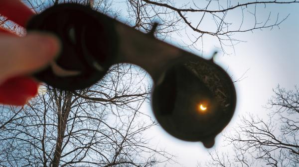 Eclipse glasses held up towards a solar eclipse.