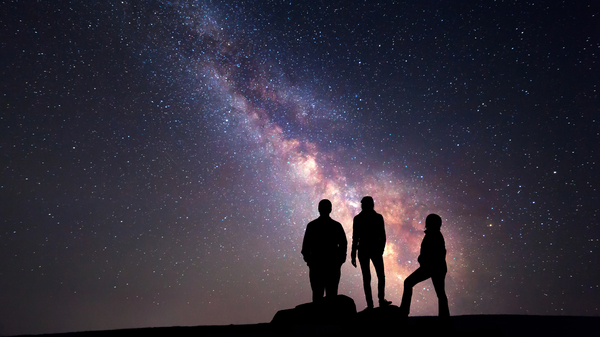 Three people gaze at the night sky.