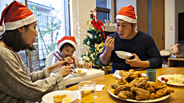 Japanese family eating fried chicken for dinner with their small child, wearing red caps