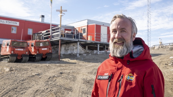 Man standing in front of Troll Research Station in Antarctica. 