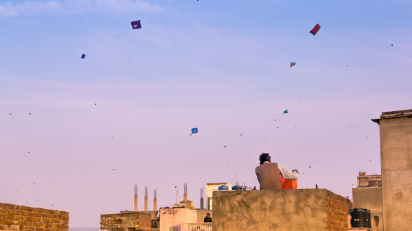 Families flying kites from the rooftops of their old brick buildings in the old city of Jaipur. This is a popular sport of Makar Sankranti and Independence Day.