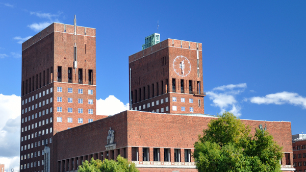 Klokken på Oslo rådhus om våren. Blå himmel og sol.