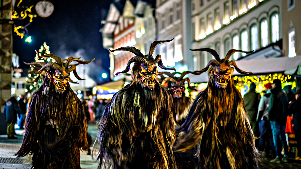 Three people in Krampus costumes at night in Bad Toelz, Germany.
