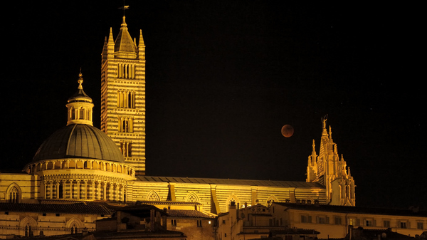 Image of a faint eclipsed Moon behind a brightly it castle.