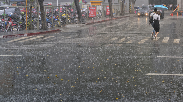 People are holding umbrellas while crossing the zebra crossing in Manila, Philippines, in a thunderstorm.